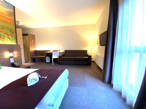 a hotel room with a bed and a couch at Hotel-Restaurant Horizon Ath-Lessines in Ghislenghien