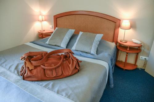 ロミイ・シュル・セーヌにあるNicey - Hôtel Spa, Lounge, Coworkingのホテルルームのベッドに座る財布
