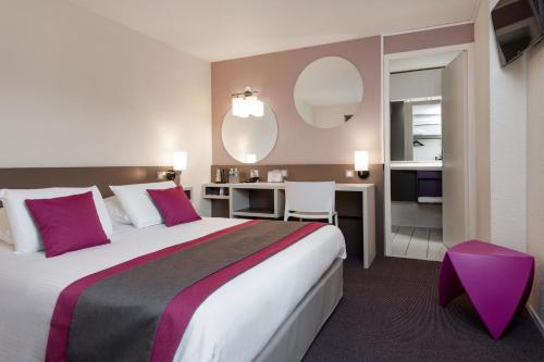 a hotel room with a large bed and a desk at Kyriad Saint-Etienne Centre in Saint-Étienne