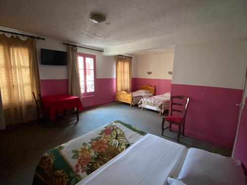 sypialnia z różowymi ścianami, łóżkiem i krzesłem w obiekcie Hotel Normandy w mieście Dreux