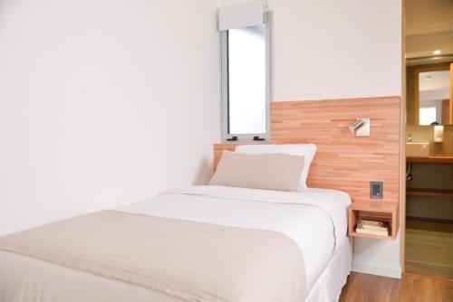 a white bed in a room with a window at TAS D VIAJE Suites - Hostel Boutique in Punta del Este