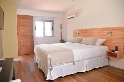 a bedroom with a large white bed with a wooden headboard at TAS D VIAJE Suites - Hostel Boutique in Punta del Este