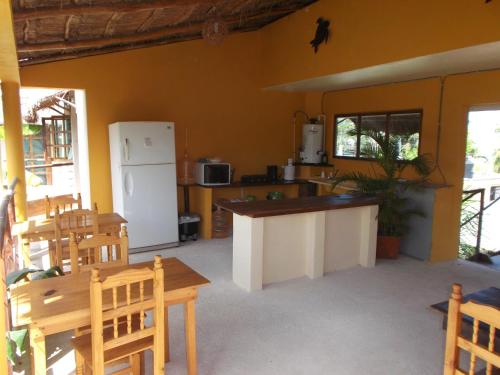 a kitchen with a white refrigerator and tables and chairs at Casa Abanico Tulum in Tulum