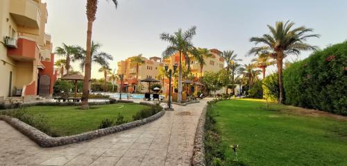 a path through a park with palm trees and buildings at Green Garden Resort in Hurghada