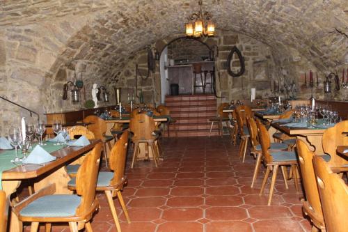 a restaurant with wooden tables and chairs in a stone building at Hotel Bayerischer Hof in Münnerstadt