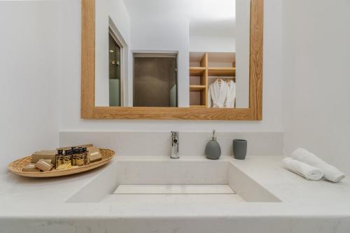 a white bathroom sink with a mirror and a counter at Symphony Suites Santorini in Pyrgos
