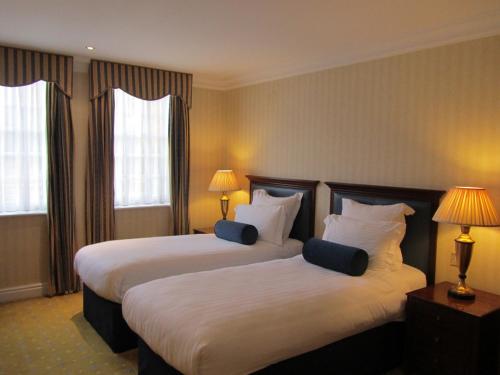 a hotel room with two beds and two windows at Manor Hotel Solihull, BW Signature Collection in Bickenhill