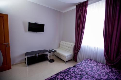 1 dormitorio con 1 cama, 1 silla y TV en Apartments Near The Airport, en Adler