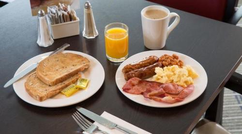 a table with two plates of breakfast food and a cup of coffee at Holiday Inn Newcastle-Jesmond, an IHG Hotel in Newcastle upon Tyne