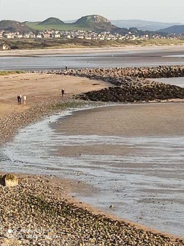 a group of people walking on the beach at THE TREVONE, Llandudno in Llandudno