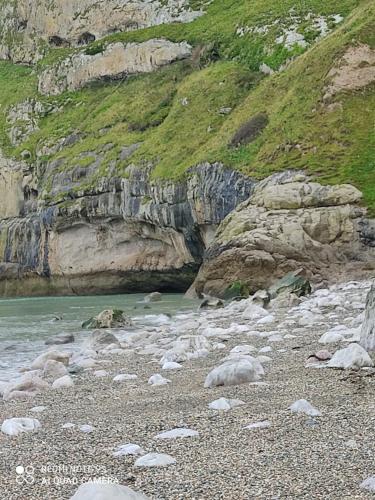a group of rocks on a beach next to a mountain at THE TREVONE, Llandudno in Llandudno