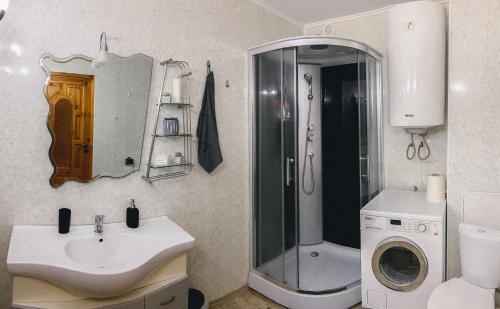 a bathroom with a sink and a shower and a washing machine at Cosy and Charming apartment in Alūksne