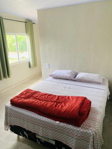 a bed with a red pillow on top of it at Repouso do Tchê in Foz do Iguaçu