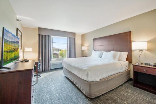 a hotel room with a large bed and a desk at Cobblestone Hotel & Suites - Austin in Austin