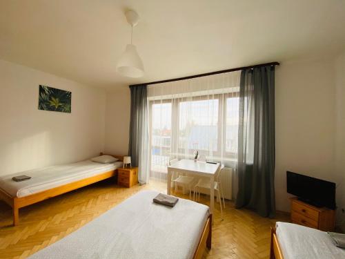 ルブリンにあるPokoje Gajowaのベッド2台、デスク、窓が備わる客室です。