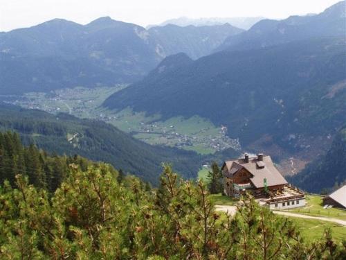 a house on a hill with mountains in the background at Appartements Pension Elfi in Gosau