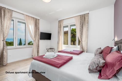 a bedroom with two beds and two windows at Apartments Liana in Opatija