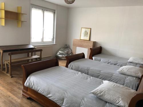 een kamer met 3 bedden en een piano bij Gîte Manava - grande maison avec jardin en centre ville in Valognes
