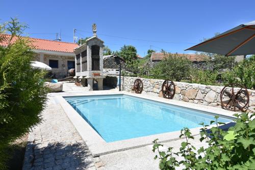 einen Pool in einem Garten mit einer Steinmauer in der Unterkunft Quinchoso dos Bentos in Vila Pouca de Aguiar