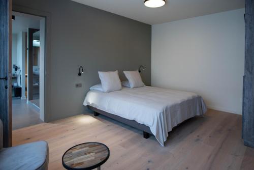 a bedroom with a bed with white sheets and a table at ‘t Ponton in Nieuwpoort