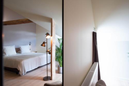a bedroom with a white bed and a mirror at ‘t Ponton in Nieuwpoort