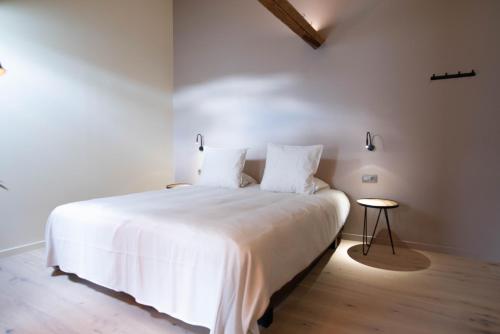 a bedroom with a bed with white sheets and a table at ‘t Ponton in Nieuwpoort