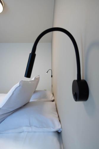a black lamp on a bed with white pillows at ‘t Ponton in Nieuwpoort