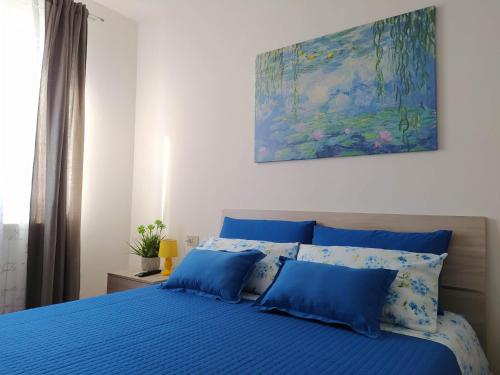 La Casa al Colle في Treglio: سرير ازرق ومخدات زرقاء ولوحة على الحائط