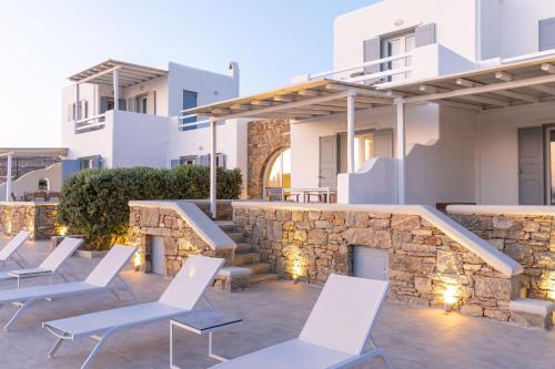 a patio with white chairs and a stone wall at Sea Wind Villas and Suites in Tourlos