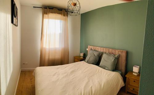 1 dormitorio con 1 cama con pared verde en Un confort chaleureux au Rendez-vous en Roques Sur Garonne