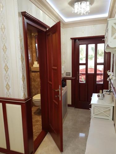 a bathroom with a toilet and a wooden door at Barackos Wellness Villa Fót in Fót