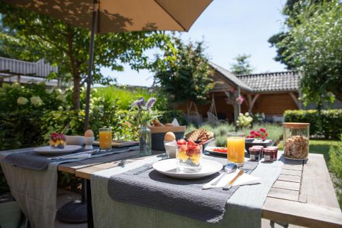 una mesa de picnic con comida y bebida y una sombrilla en Bed & Breakfast Monument076 Etten-Leur en Etten-Leur