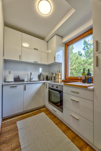une cuisine avec des armoires blanches et une fenêtre dans l'établissement Apartment Grey Mountain, à Zlatibor