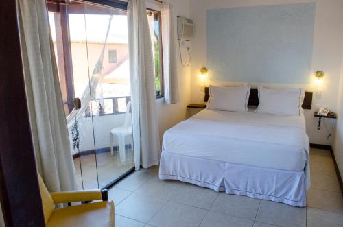 a bedroom with a white bed and a balcony at Guest House Green Garden in Búzios