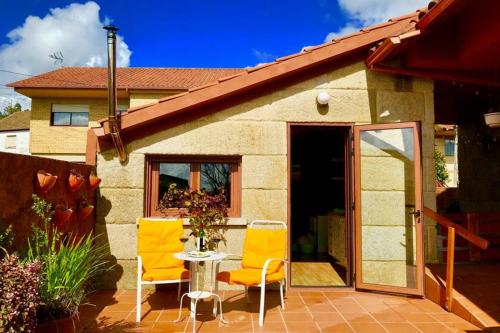 a patio with two chairs and a table in front of a house at Tranquila casita de invitados en Vigo con chimenea in Vigo