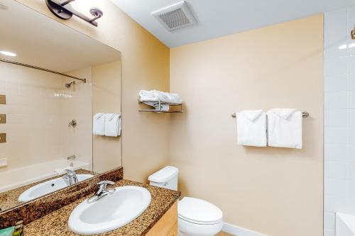 W łazience znajduje się umywalka, toaleta i lustro. w obiekcie Founders Pointe Condo w mieście Winter Park