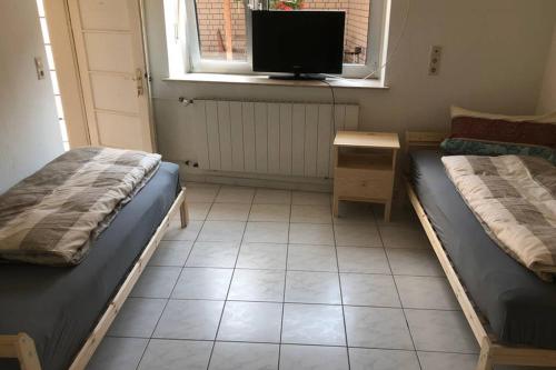 two beds in a room with a tv and a desk at room for four in Alzenau in Unterfranken