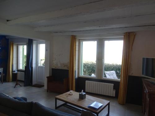 a living room with a couch and a table and windows at La maison de Gaston in Le Port-des-Barques