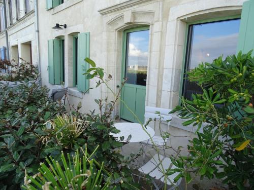 a building with green doors and some plants at La maison de Gaston in Le Port-des-Barques
