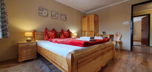 Un dormitorio con una gran cama de madera con almohadas rojas en Privát u Babičky, en Ždiar