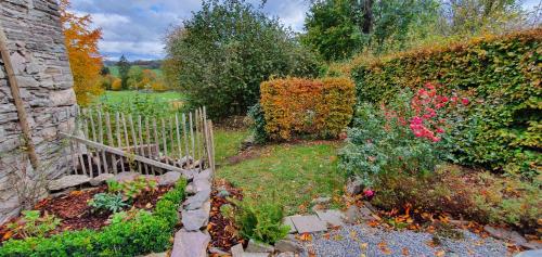 a garden with a wooden fence and flowers at O Près de la Lienne, maison de campagne de charme, accord parfait entre confort et authenticité in Lierneux