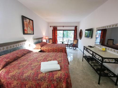 a hotel room with two beds and a desk at Hotel Doralba Inn in Mérida