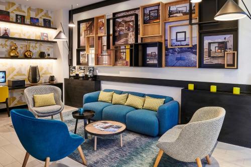 - un salon avec un canapé bleu et des chaises dans l'établissement Holiday Inn Nice, an IHG Hotel, à Nice
