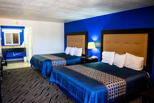 two beds in a hotel room with blue walls at Blue Jay Inn & Suites in Sallisaw