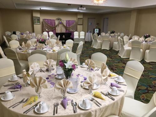 a banquet hall with white tables and white chairs at Holiday Inn Westbury-Long Island by IHG in Carle Place