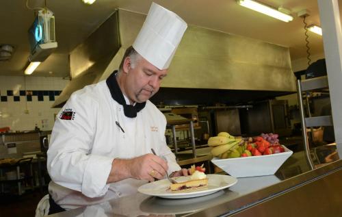 a chef preparing a plate of food in a kitchen at Holiday Inn Telford Ironbridge by IHG in Telford