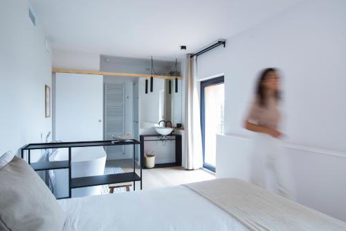 Hotel Rural Mas de l'Illa في Tivissa: امرأة تقف في غرفة نوم بسرير