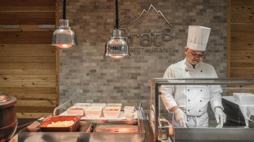 un chef de pie en una cocina preparando comida en Holiday Inn Munich City Centre by IHG, en Múnich