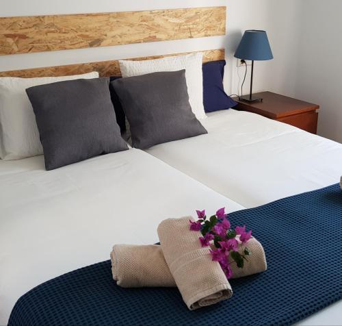 a bed with two pillows and flowers on it at Avenue Puerto del Carmen in Puerto del Carmen