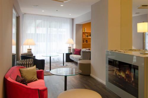 a living room with red chairs and a fireplace at Holiday Inn Vienna City by IHG in Vienna